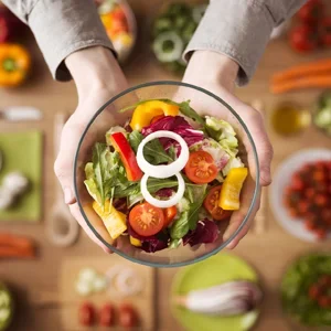 Hands holding a salad with brightly colored vegetables